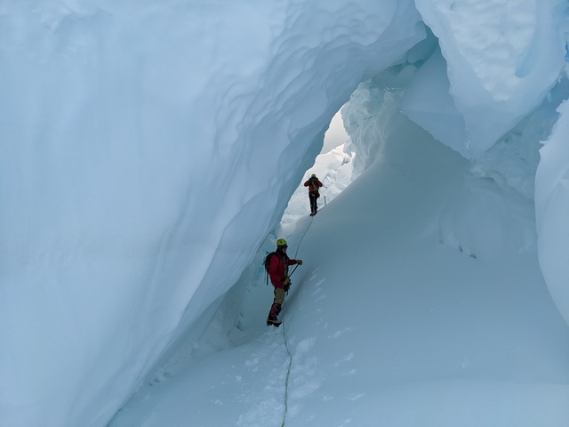 2 people stand in an ice cave covered in snow