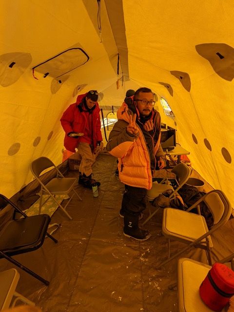 Three people standing inside the ktichen tent