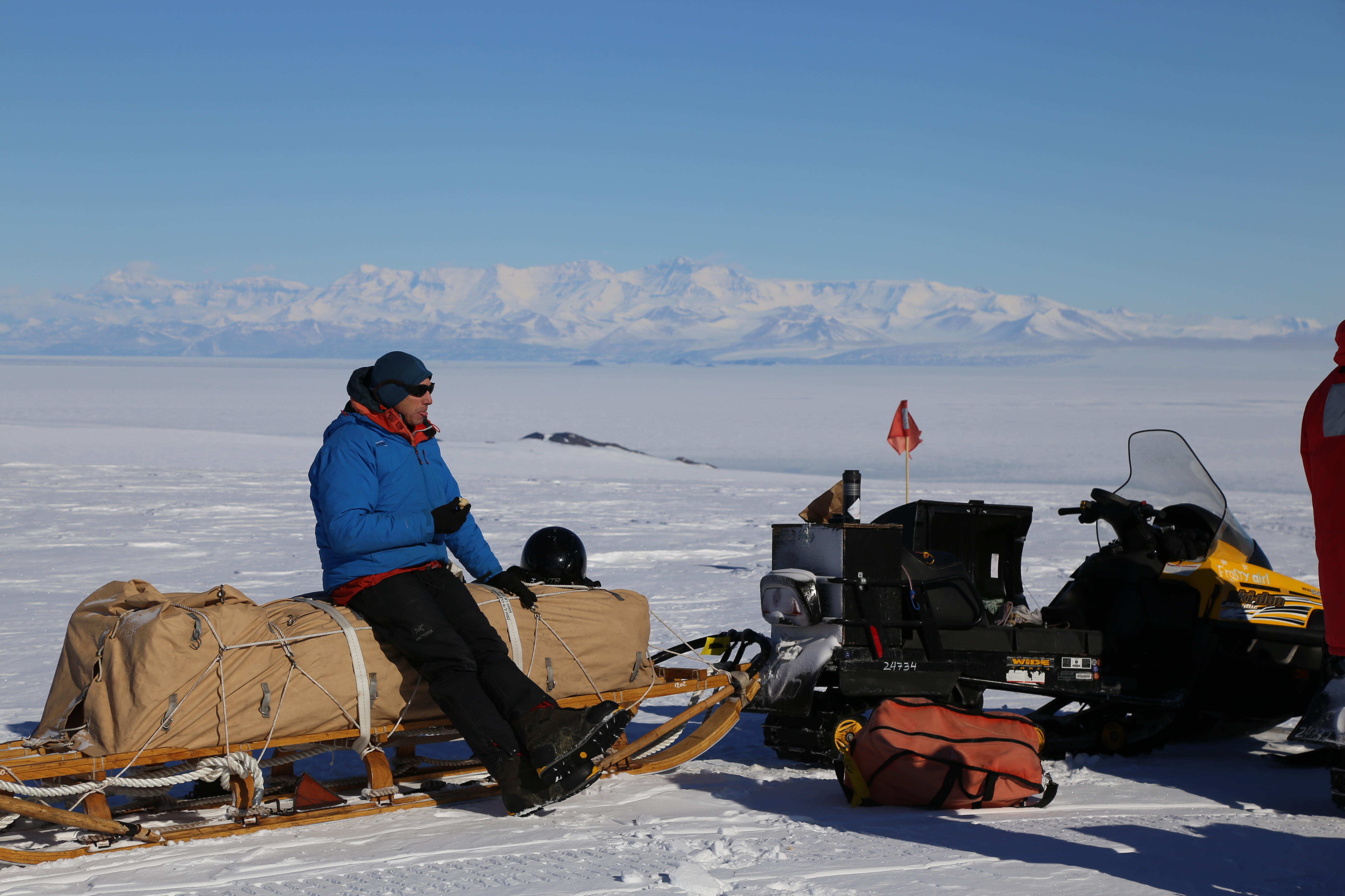 Man sitting on a snowmobile eating lunch