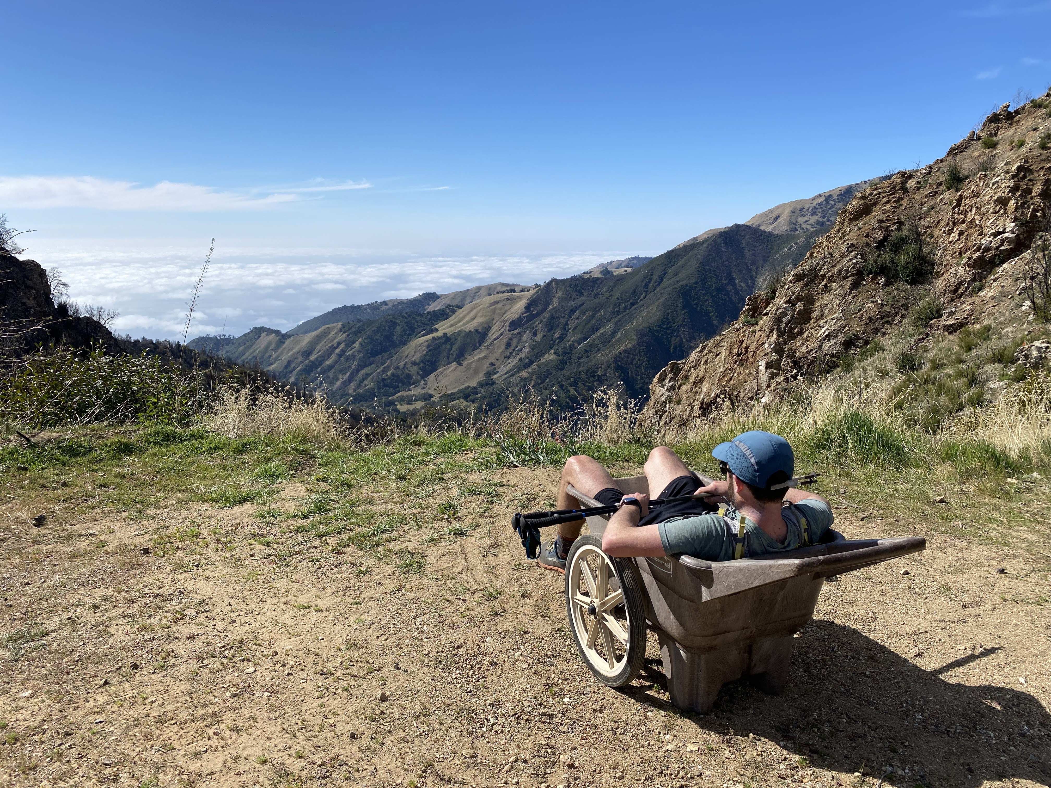 Paul sitting in a wheelbarrow overlooking an ocean view