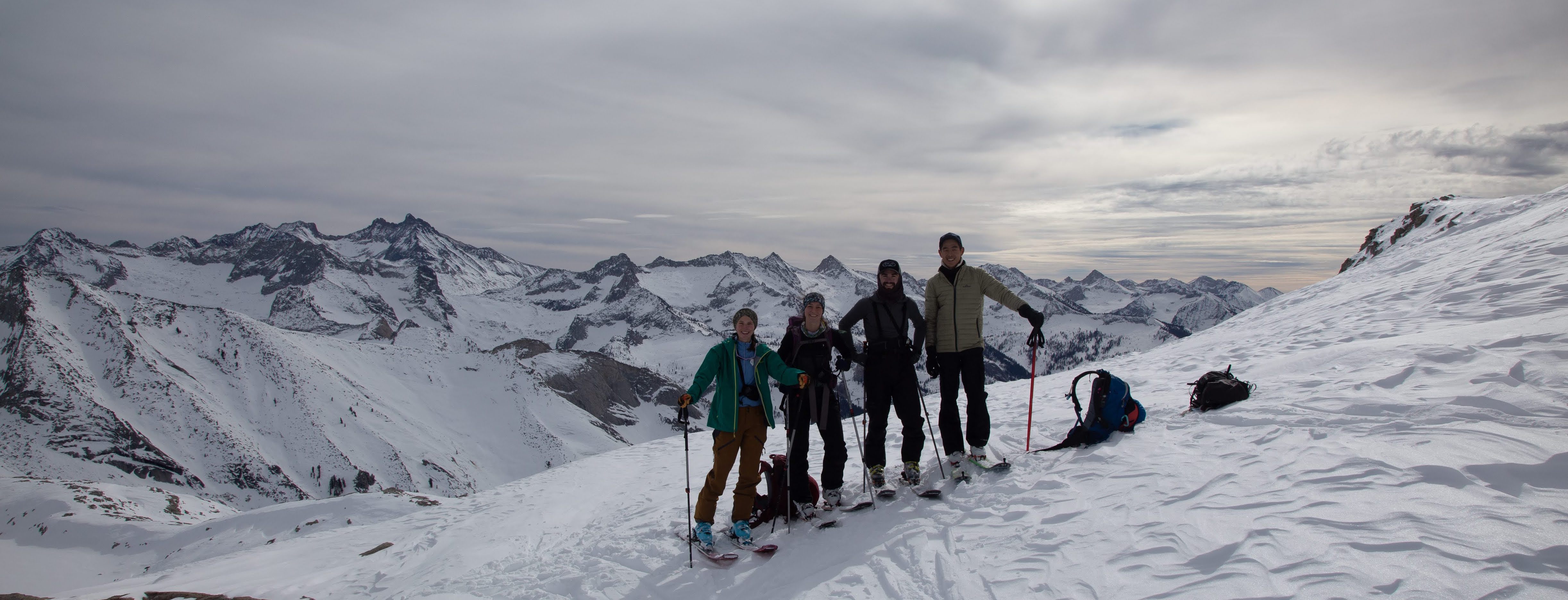 4 people on skis pose for a picture on a mountain ridgeline